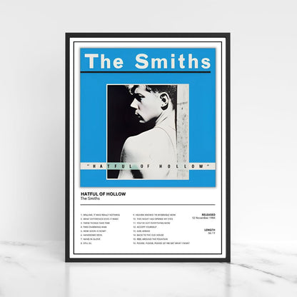 A framed music poster of The Smiths' album 'Hatful of Hollow' displayed on a light marble surface against a white wall. The poster features a bright blue background, a black-and-white portrait of the band, and white text, enclosed in a black frame.