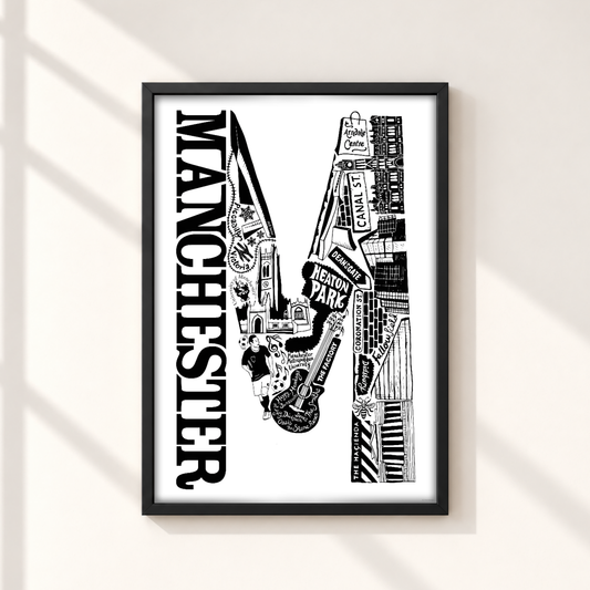 A framed black and white art print featuring the word 'MANCHESTER' in large vertical letters alongside an illustrated cityscape with musical instruments, displayed on a light beige wall with soft window shadow lines.
