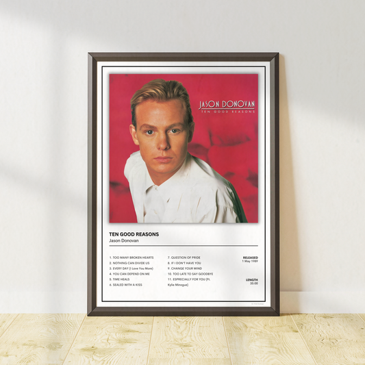 Jason Donovan Ten Good Reasons album cover and tracklist poster print in a black frame leaning against a neutral wall with light wood flooring.