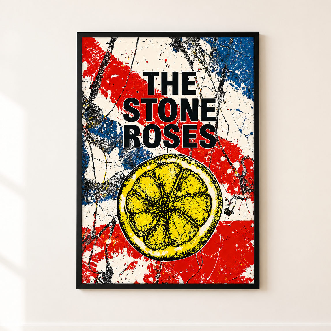 A framed art print of The Stone Roses album cover, featuring a yellow lemon slice over a distressed red, white, and blue background, displayed on a light beige wall.