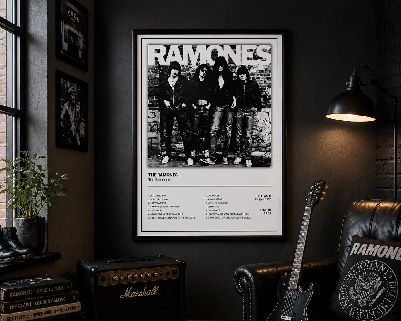 A framed black and white Ramones concert poster hangs on a dark wall in a styled room with a guitar, Marshall amp, plant, and lamp.