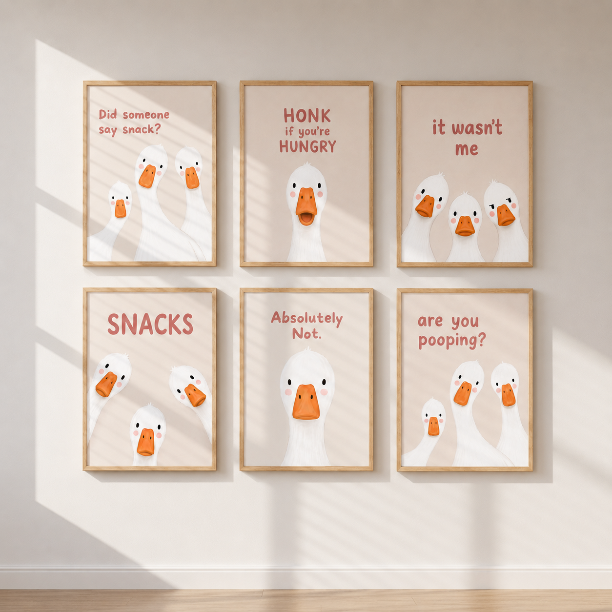 Six framed duck-themed wall art prints arranged in a 2x3 grid on a beige wall with soft window shadows. The prints feature white ducks with orange beaks and humorous phrases such as 'Did someone say snack?', 'HONK if you're HUNGRY', 'it wasn't me', 'SNACKS', 'Absolutely Not.