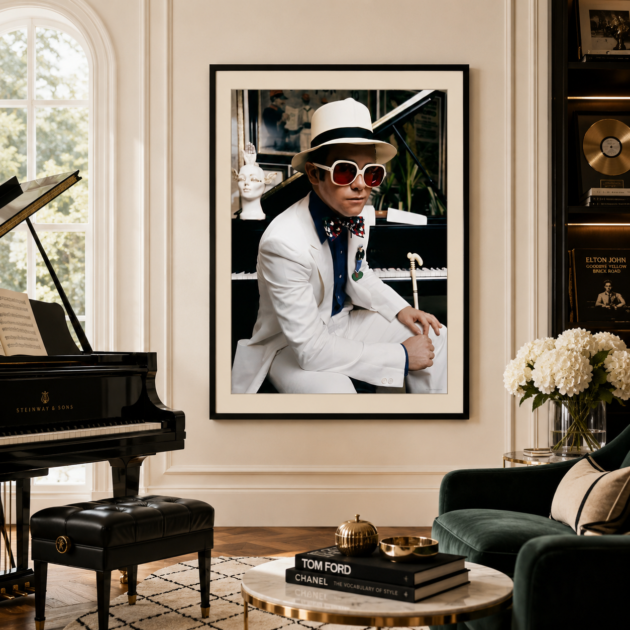 A framed vertical art print of Elton John in a white suit and hat, displayed on a beige wall in a beautifully decorated living room with a grand piano, green armchair, and coffee table.
