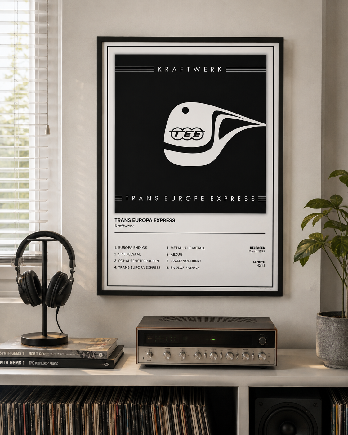 A framed black and white Trans Europe Express poster hangs on a light gray wall above a shelf with headphones, records, an audio receiver, and a potted plant.