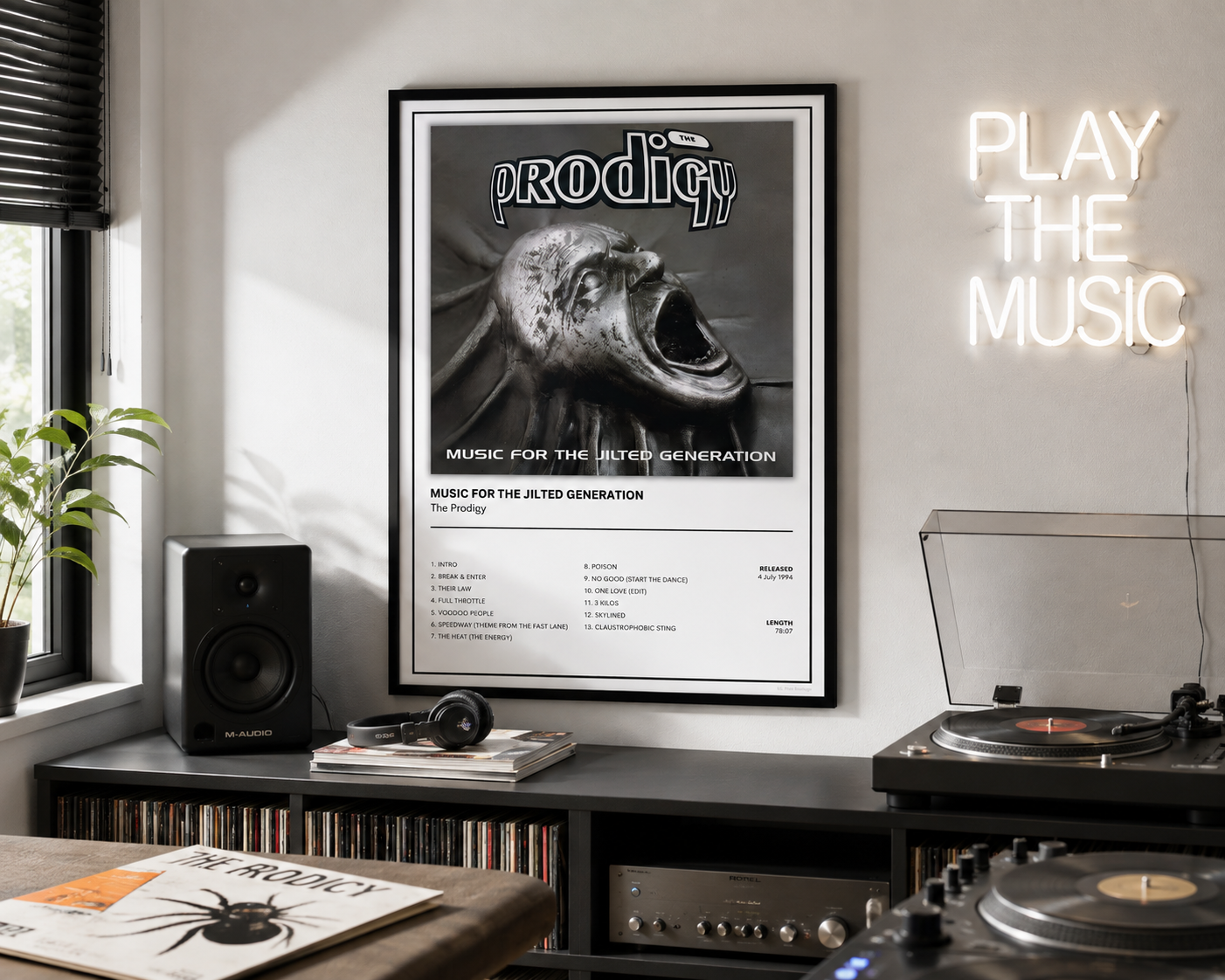 A framed black and white music poster for the band Prodigy hangs on a wall in a styled music room setting with a glowing neon 'PLAY THE MUSIC' sign, a speaker, vinyl records, and a turntable.