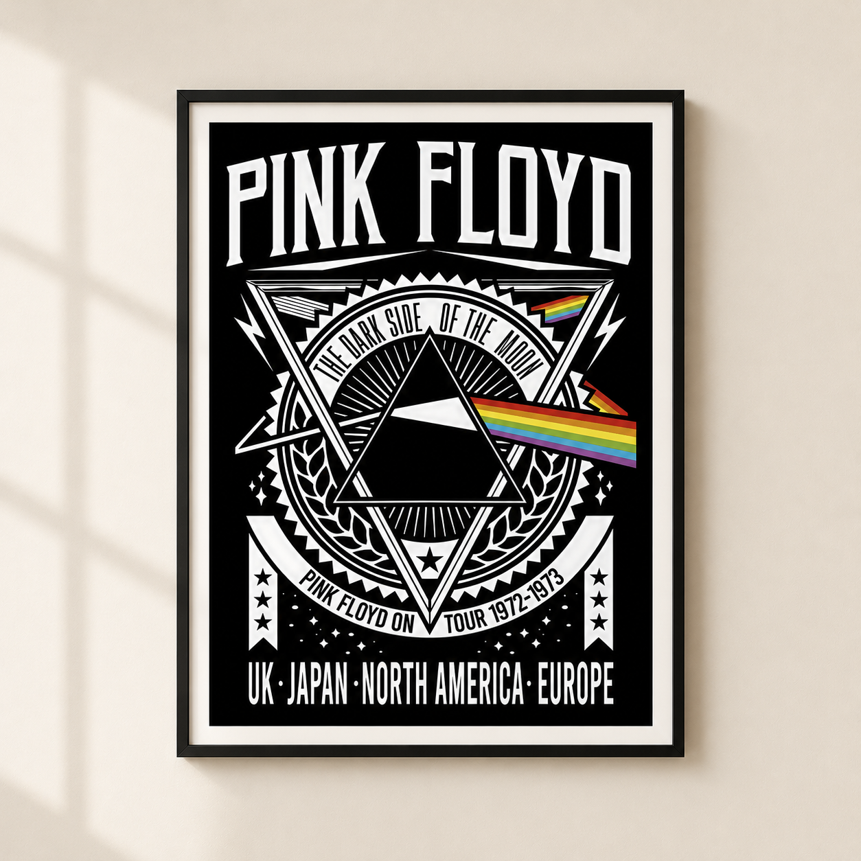 A framed Pink Floyd 'The Dark Side of the Moon' poster hanging on a light beige wall. The poster features a black background with white text and graphics, including the band name 'PINK FLOYD', a triangular prism design, and a rainbow light beam.