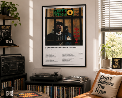 A framed Public Enemy 'It Takes A Nation Of Millions To Hold Us Back' music poster hanging on a wall in a styled room with a turntable, records, and a pillow.