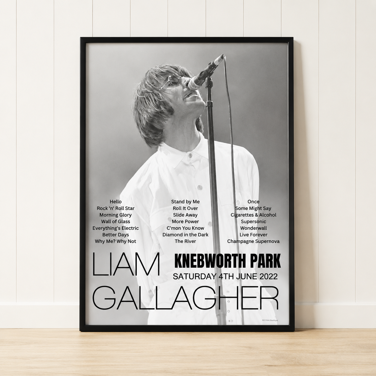 Liam Gallagher Knebworth Park 2022 concert poster print in a black frame leaning against a minimalist cream panelled wall.
