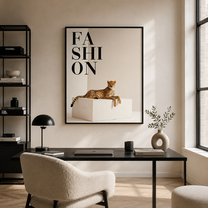 A framed fashion poster featuring a leopard on a white block with the word 'FASHION' hangs on a beige wall above a modern desk setup in a styled home office.