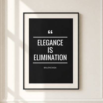 A framed minimalist quote print hanging on a cream-colored wall with decorative molding and soft window shadows. The print features a black background with white text reading 'ELEGANCE IS ELIMINATION' and the Balenciaga name at the bottom.