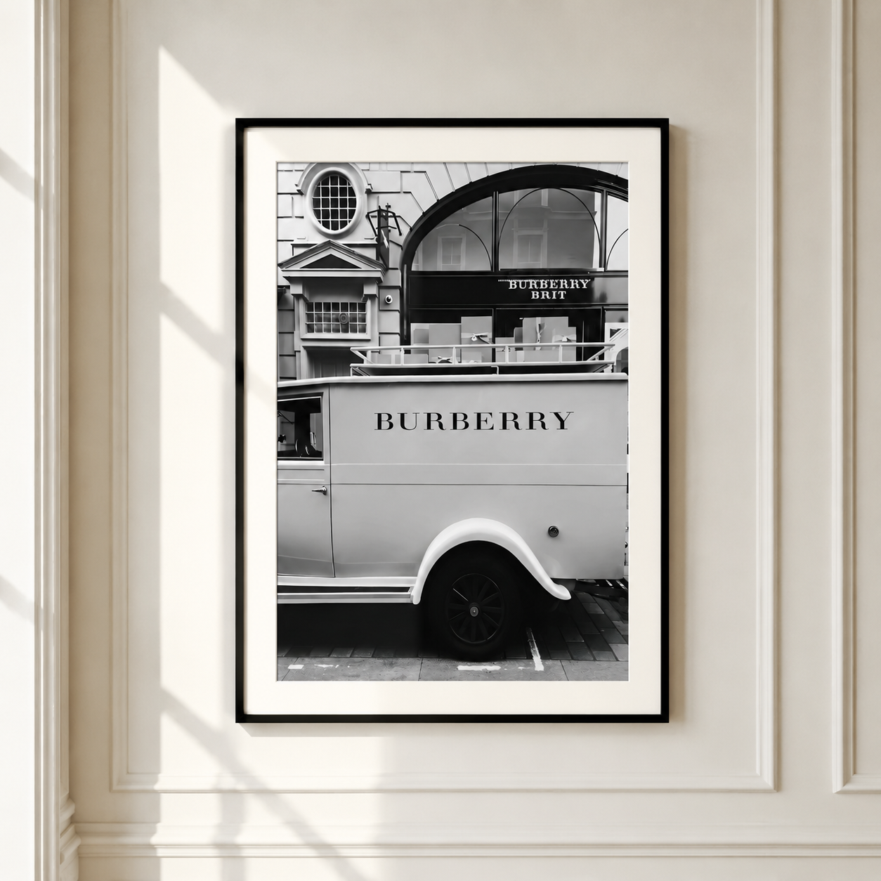 A framed black and white art print of a vintage Burberry delivery van parked in front of a Burberry store, mounted on a white paneled wall.