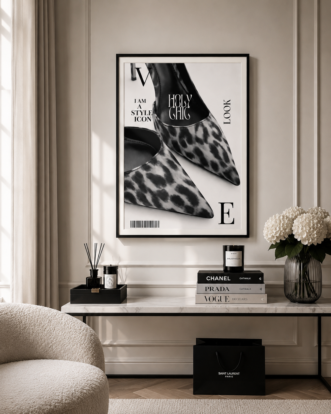 A framed black and white fashion poster featuring leopard-print pointed shoes and editorial text, displayed on a beige wall above a console table with books, a candle, and flowers.