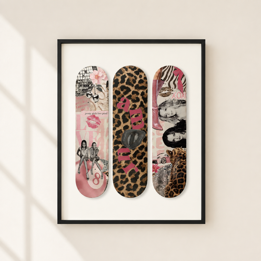 A framed wall art print featuring three vertical skateboard-deck style collage designs in pink, leopard print, and mixed-media tones, hung on a light beige wall with soft window-shadow lighting.