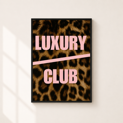 A framed poster with a leopard print background and the words 'LUXURY CLUB' in pink lettering, hanging on a light beige wall with soft window shadows.