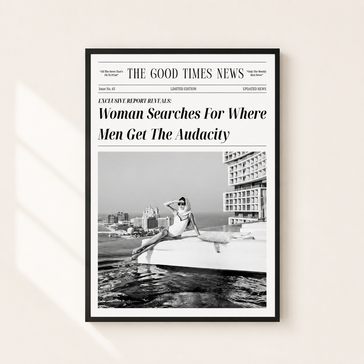 A framed black-and-white newspaper-style poster hanging on a light beige wall. The poster mimics a newspaper front page with the headline 'Woman Searches For Where Men Get The Audacity' and a black-and-white photo of a woman sitting on a boat.