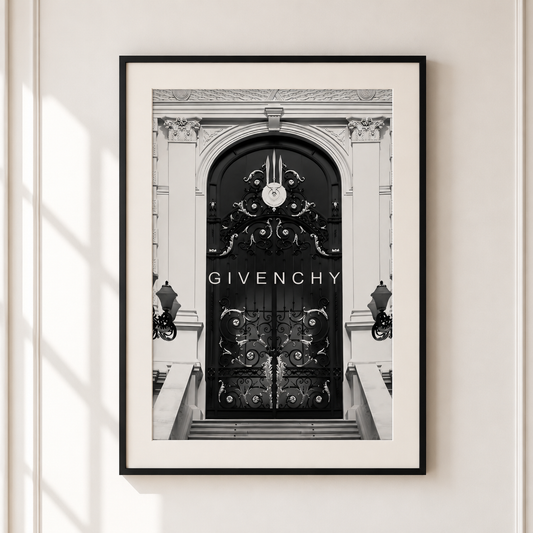A framed black and white art print of a Givenchy door, featuring the brand name 'GIVENCHY' in white text on the dark door. The print is framed in black with a white mat, hanging on a light beige wall.