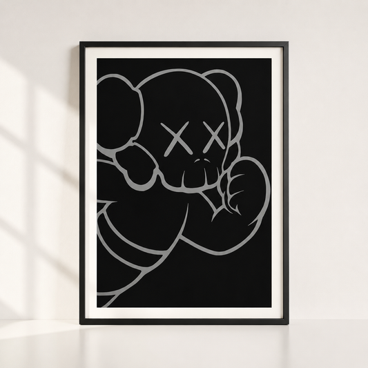 A framed art print featuring a minimalist black and white line drawing of a bear with an X for a eye, styled leaning against a white wall with soft window shadows.