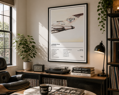 A framed music poster featuring a vintage airplane and the text 'LOVED TO SEE BEASTIE Boys Own' hangs on a wall in a styled room with a desk, lamp, plants, and records.