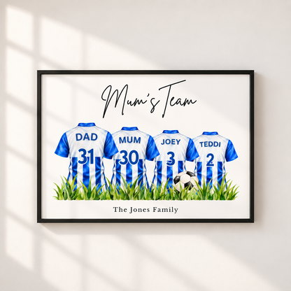 A framed personalized wall art print showing four soccer jerseys labeled DAD, MUM, JOEY, and TEDDI with numbers 31, 30, 3, and 2, above green grass and a small soccer ball. The print reads 'Mum's Team' and 'The Jones Family,' displayed on a light wall with soft window shadows.