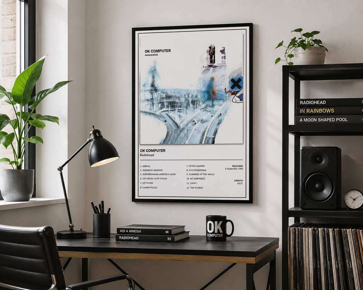 A framed art print featuring the OK Computer album cover design, hanging on a wall in a modern, styled home office setting with a desk, lamp, and shelving.