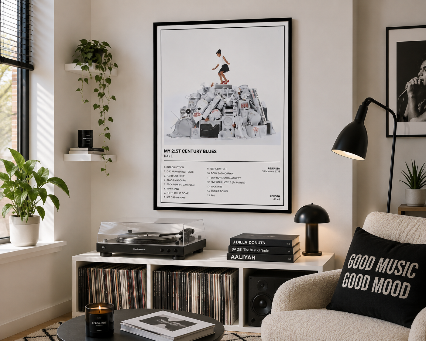 A framed music poster titled 'MY 21ST CENTURY BLUES' hangs on a wall in a styled living room. The poster features a black-and-white photo of a person standing on a pile of records, with tracklist text below.