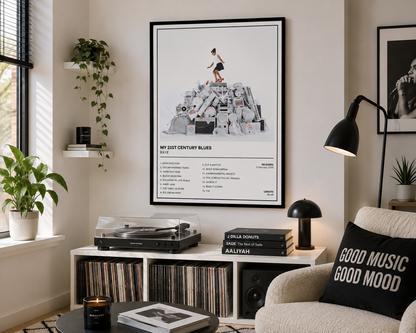 A framed music poster titled 'MY 21ST CENTURY BLUES' hangs on a wall in a styled living room. The poster features a black-and-white photo of a person standing on a pile of records, with tracklist text below.