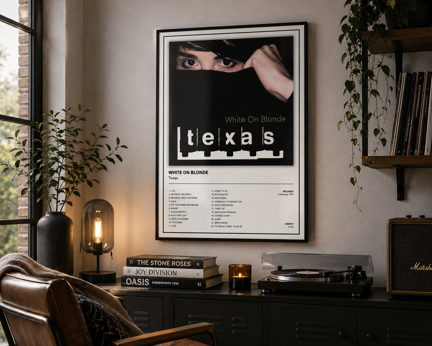 A framed 'White On Blonde' Texas album poster hangs on a beige wall in a styled room setting with a record player, books, plants, and a leather chair.