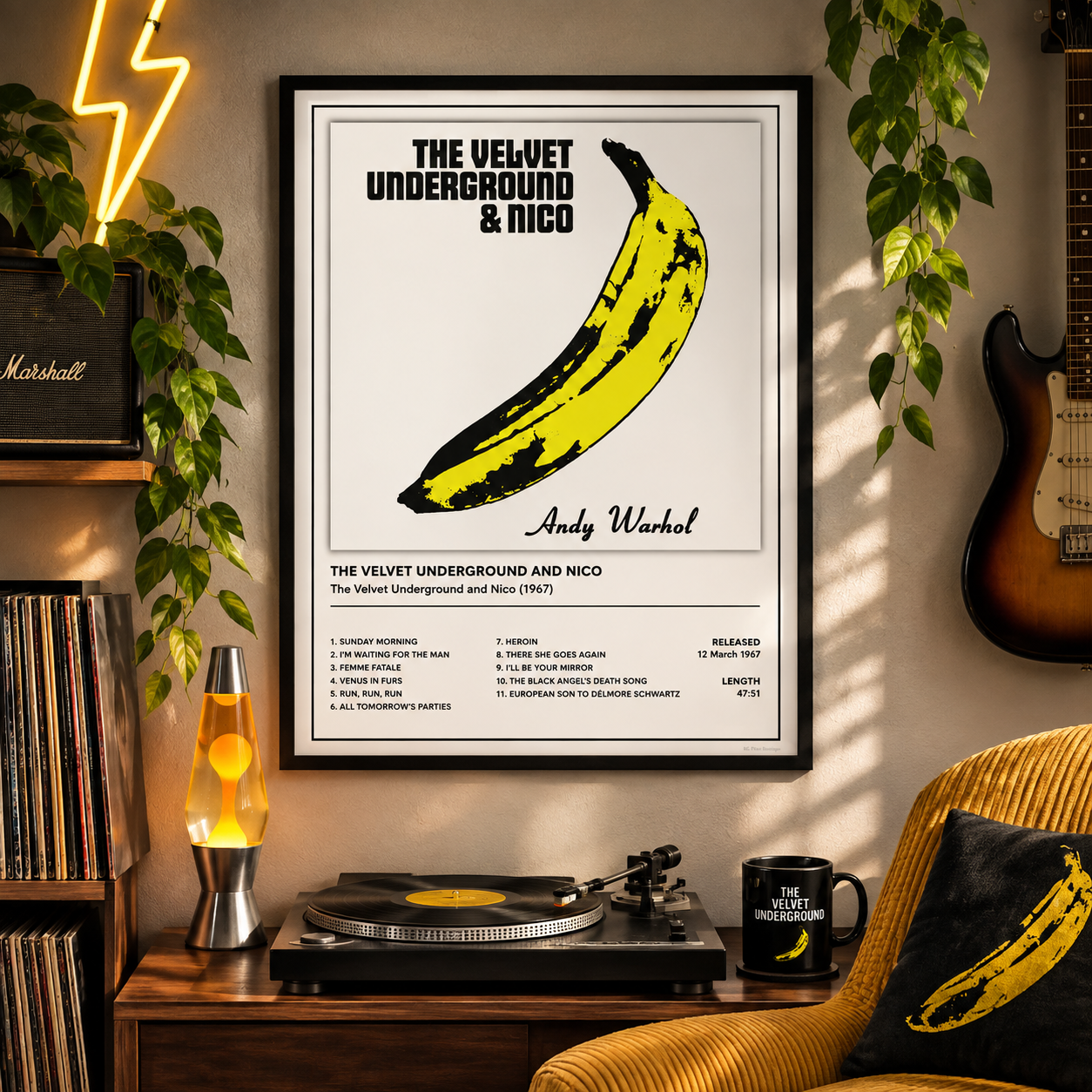 A framed Andy Warhol poster of The Velvet Underground & Nico hangs on a beige wall in a styled room with a record player, lamp, guitar, plants, and a matching yellow-and-black pillow.