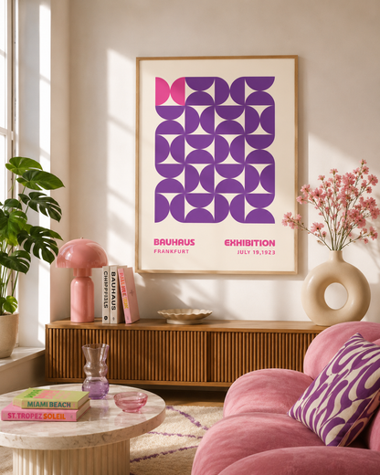 A framed art print featuring a retro geometric pattern in purple, pink, and white, displayed on a beige wall above a mid-century modern wooden console table in a styled living room.