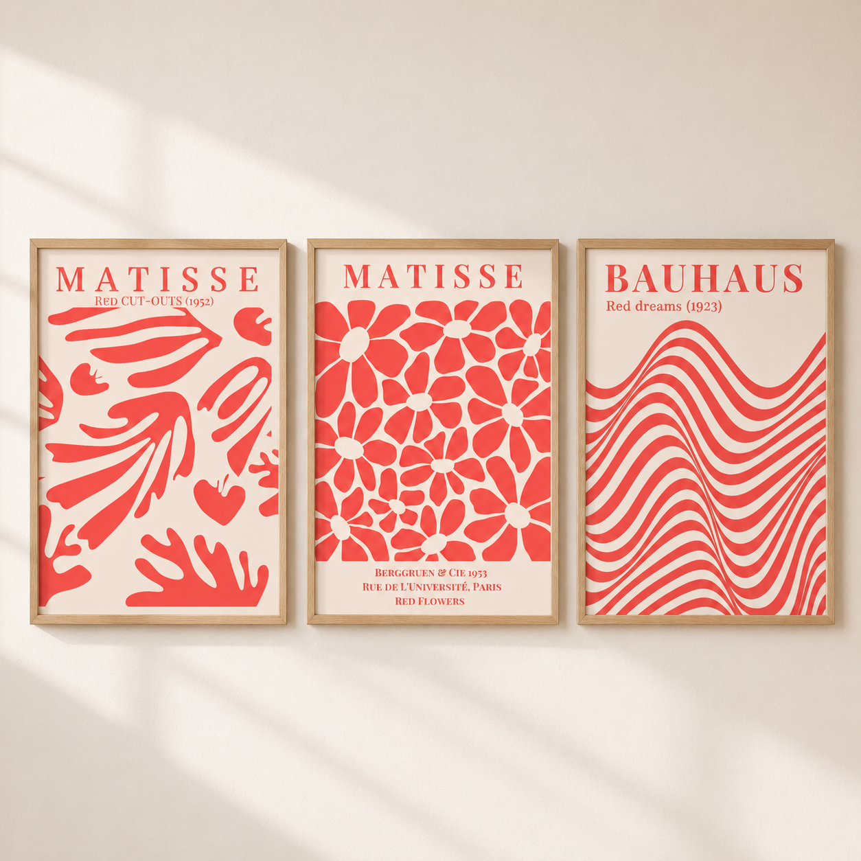 Three framed Matisse and Bauhaus art prints in a warm beige room with soft window shadows. The prints feature bold red abstract patterns on a cream background, including floral, wavy, and geometric designs.
