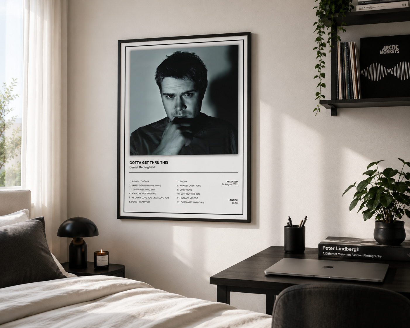 A framed black and white poster of Daniel Bedingfield titled 'Gotta Get Thru This' hanging on a light beige wall in a modern, sunlit bedroom setting.