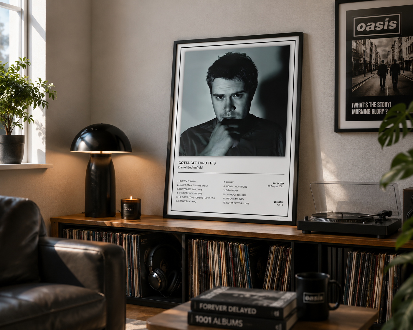 A framed black-and-white music poster for Daniel Bedingfield album displayed on a wooden record shelf in a cozy, sunlit living room. The poster features a portrait of David Gilmour and tracklist text at the bottom.