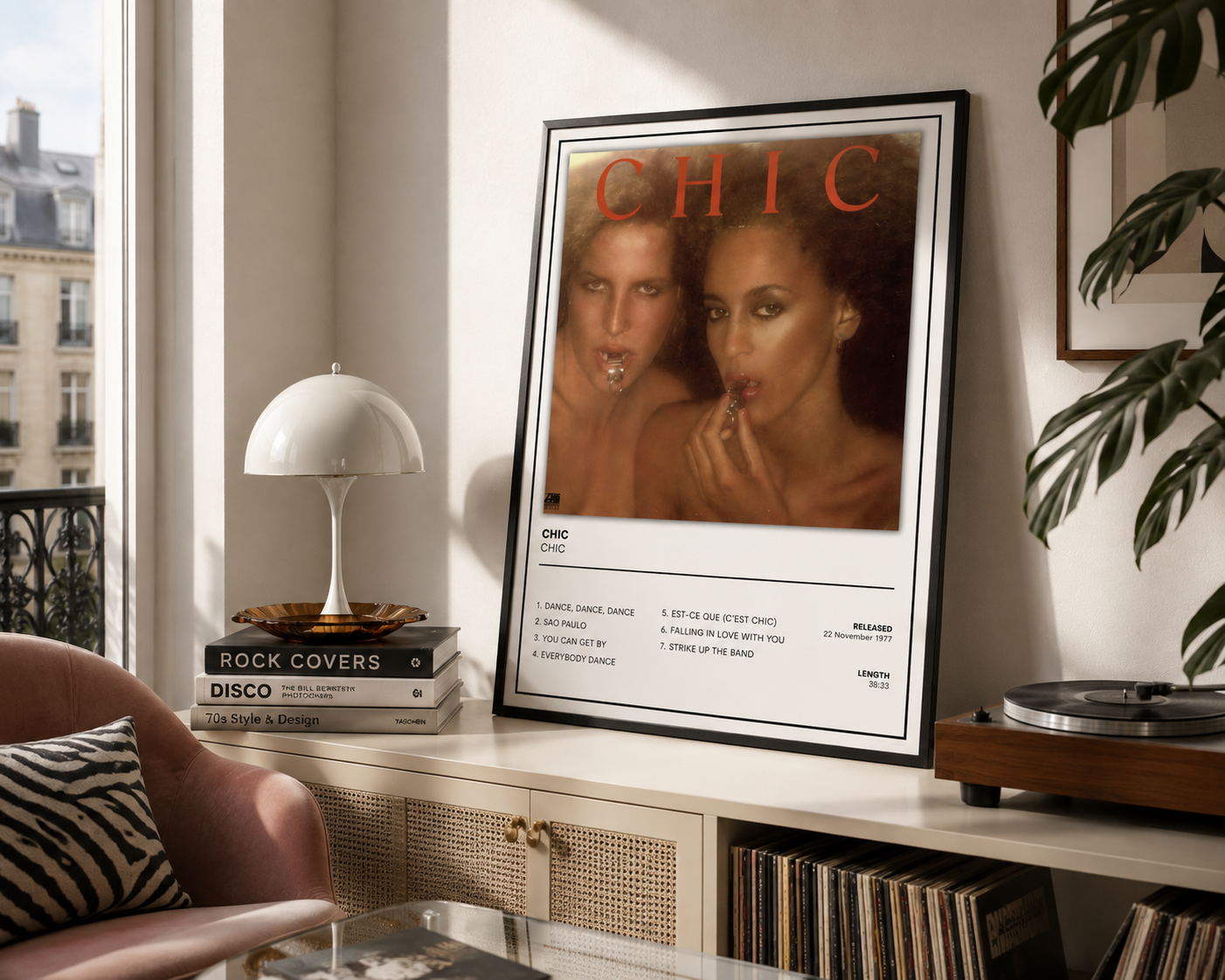 A framed music poster with the word 'CHIC' and tracklist styling leans on a shelf in a styled room with a lamp, records, and a record player.
