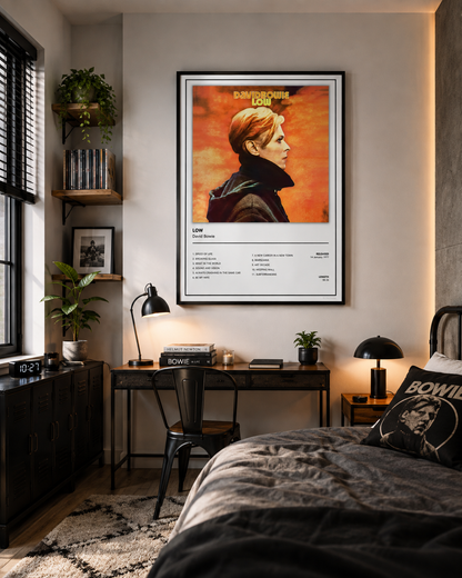 A framed David Bowie 'Low' poster hangs on a bedroom wall above a desk and bed. The poster features a stylized portrait of Bob Dylan against a fiery orange background with white text details below.