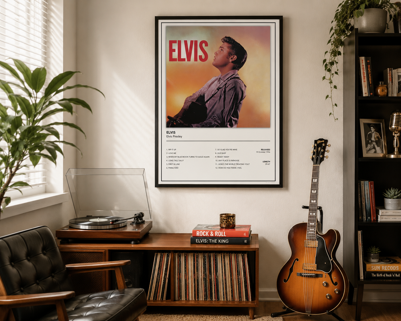 A framed Elvis Presley 'Blue and Gray' album poster hangs on a wall in a styled room with a record player, guitar, chair, and bookshelf.