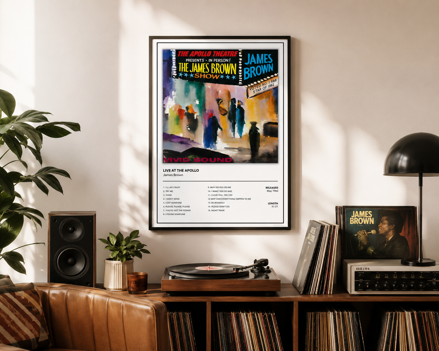 A framed James Brown 'The Apollo Theater New York City' concert poster hangs on a wall in a styled living room setting with a leather couch, record player, speakers, and a lamp.