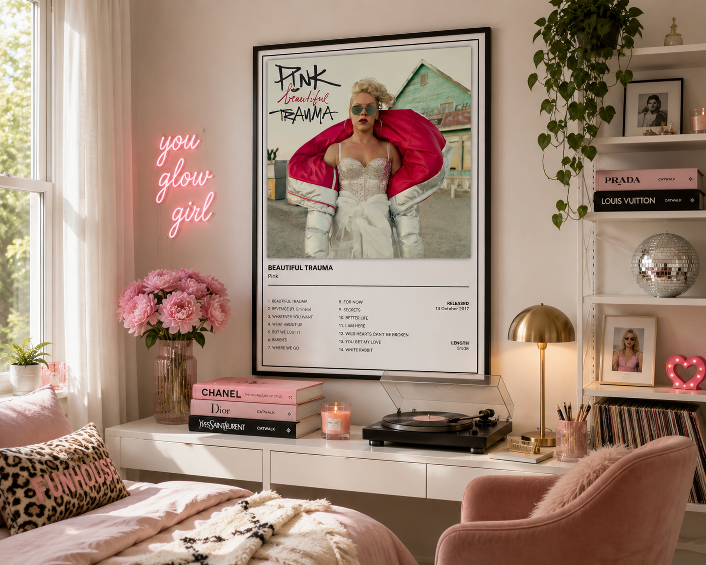 A framed 'Pink, Beautiful Trauma' poster hangs on a wall in a styled bedroom setting. The room features a pink neon sign reading 'you glow girl', a bed with pink bedding, a pink armchair, a turntable, and shelves with books and decor.