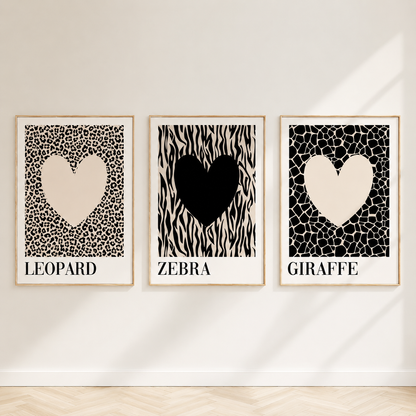 Neutral animal print gallery wall featuring leopard, zebra and giraffe heart artwork in light oak frames displayed against a bright minimalist wall.
