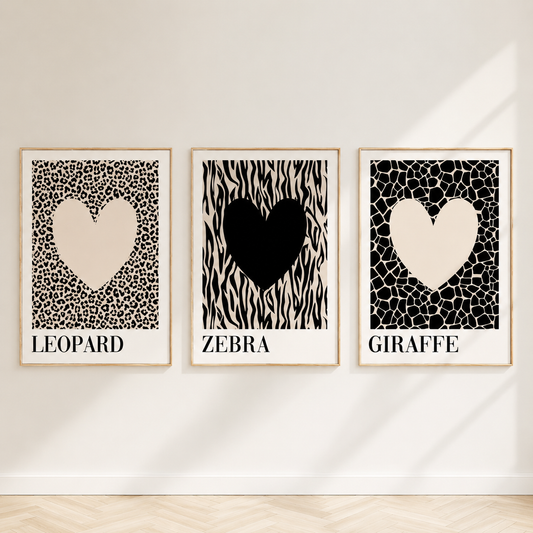 Neutral animal print gallery wall featuring leopard, zebra and giraffe heart artwork in light oak frames displayed against a bright minimalist wall.