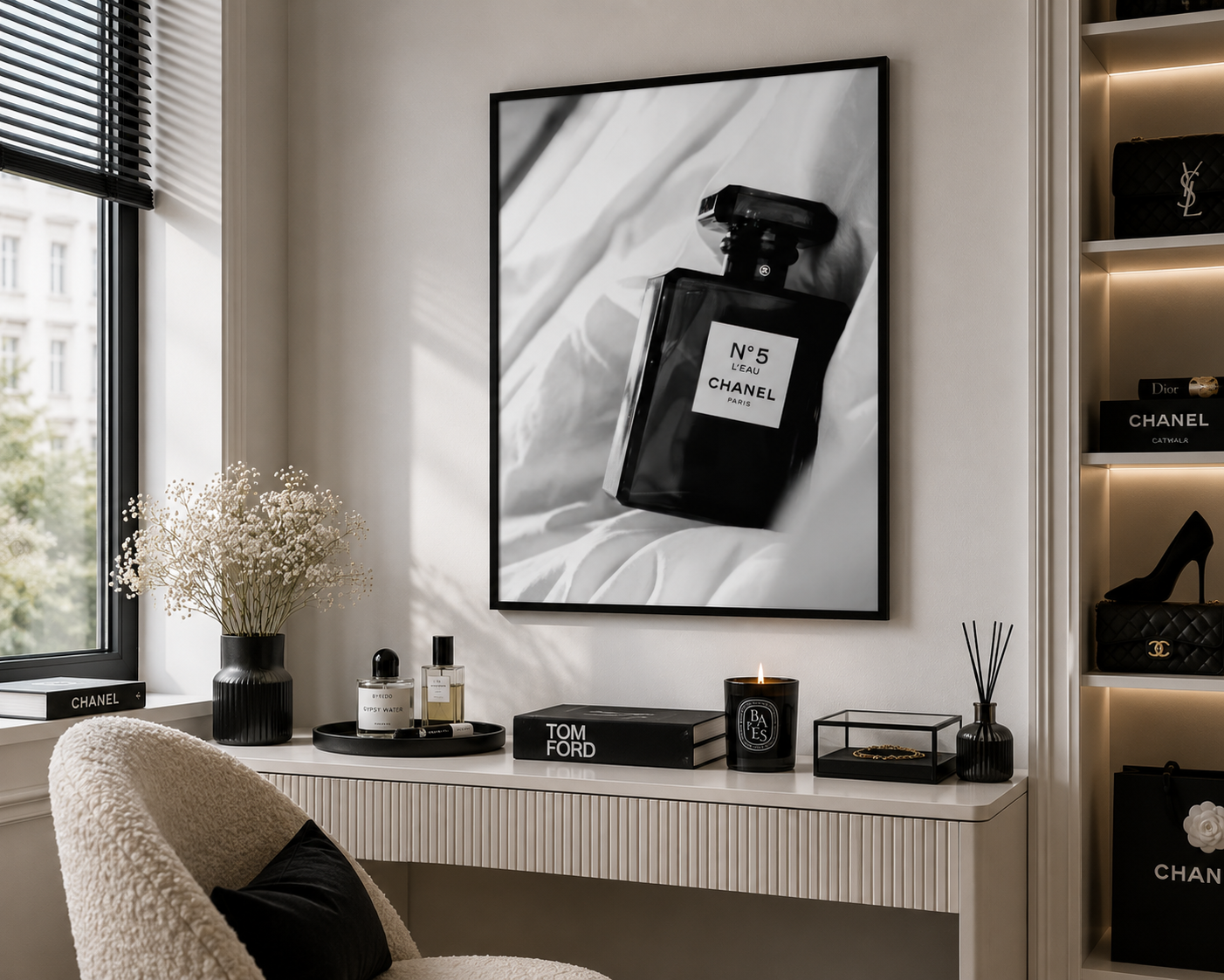 A framed black and white art print of a Chanel No. 5 perfume bottle hanging on a wall above a console table in a modern, stylishly decorated room.