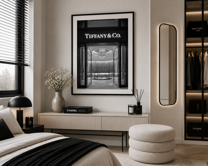 A framed black and white Tiffany & Co. architectural print hangs on a beige wall in a modern, stylishly decorated bedroom.