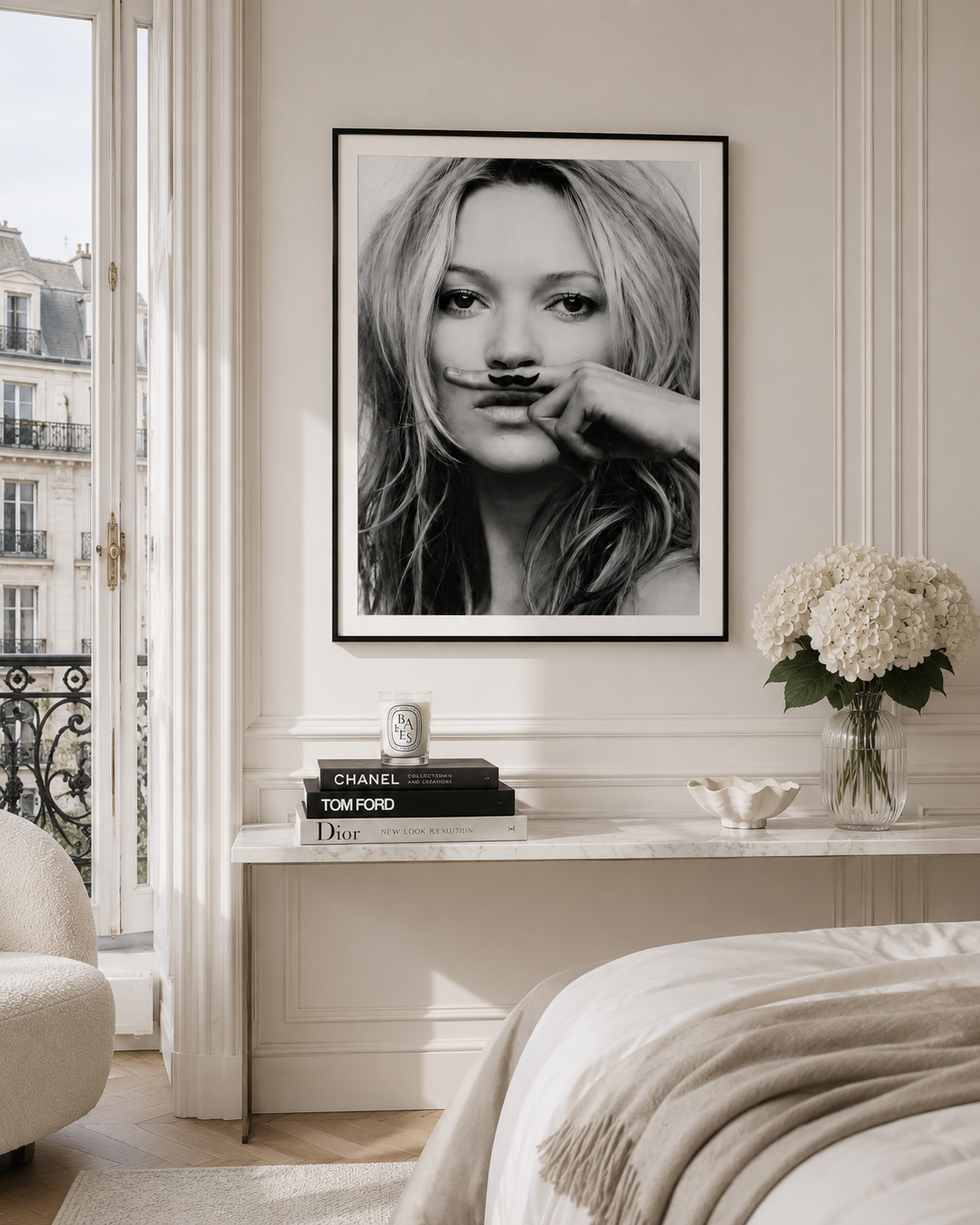 A black and white framed poster of a woman with a mustache hanging on a cream-colored wall in a styled bedroom setting.
