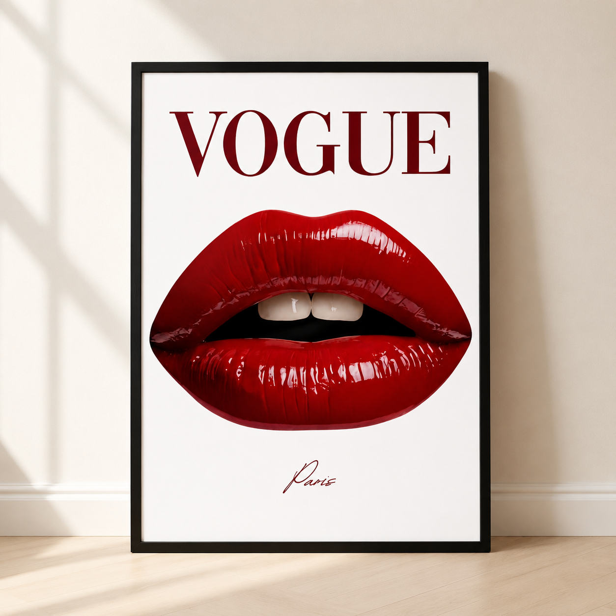 A framed Vogue art print leaning against a beige wall on a light wood floor. The print features a large pair of glossy red lips on a white background with the word 'VOGUE' in dark red serif letters at the top and a small signature reading 'Paris' below.
