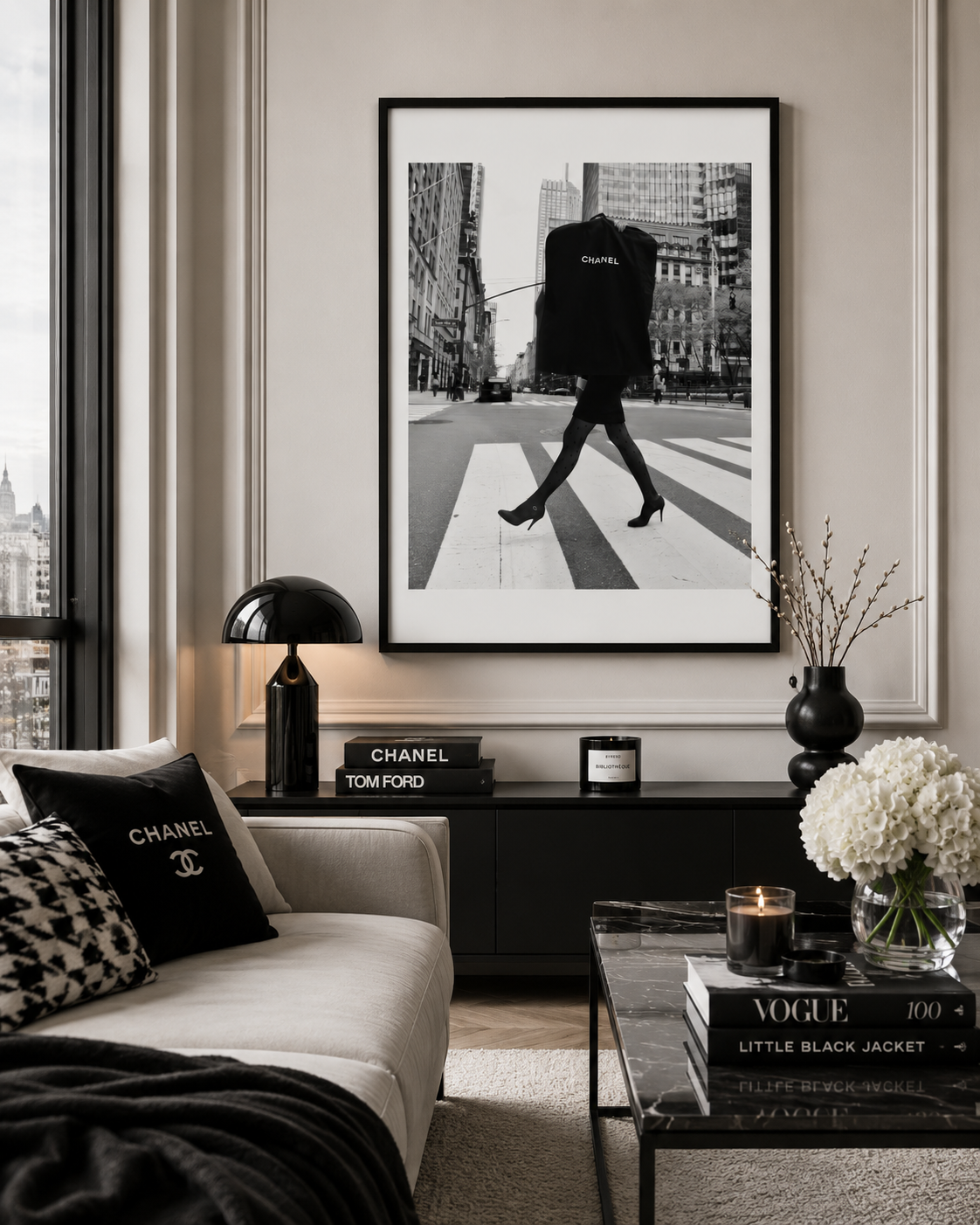 A framed black and white fashion art print of a person walking across a city crosswalk, hanging on a beige wall in a modern styled living room with a sofa, lamp, and coffee table.