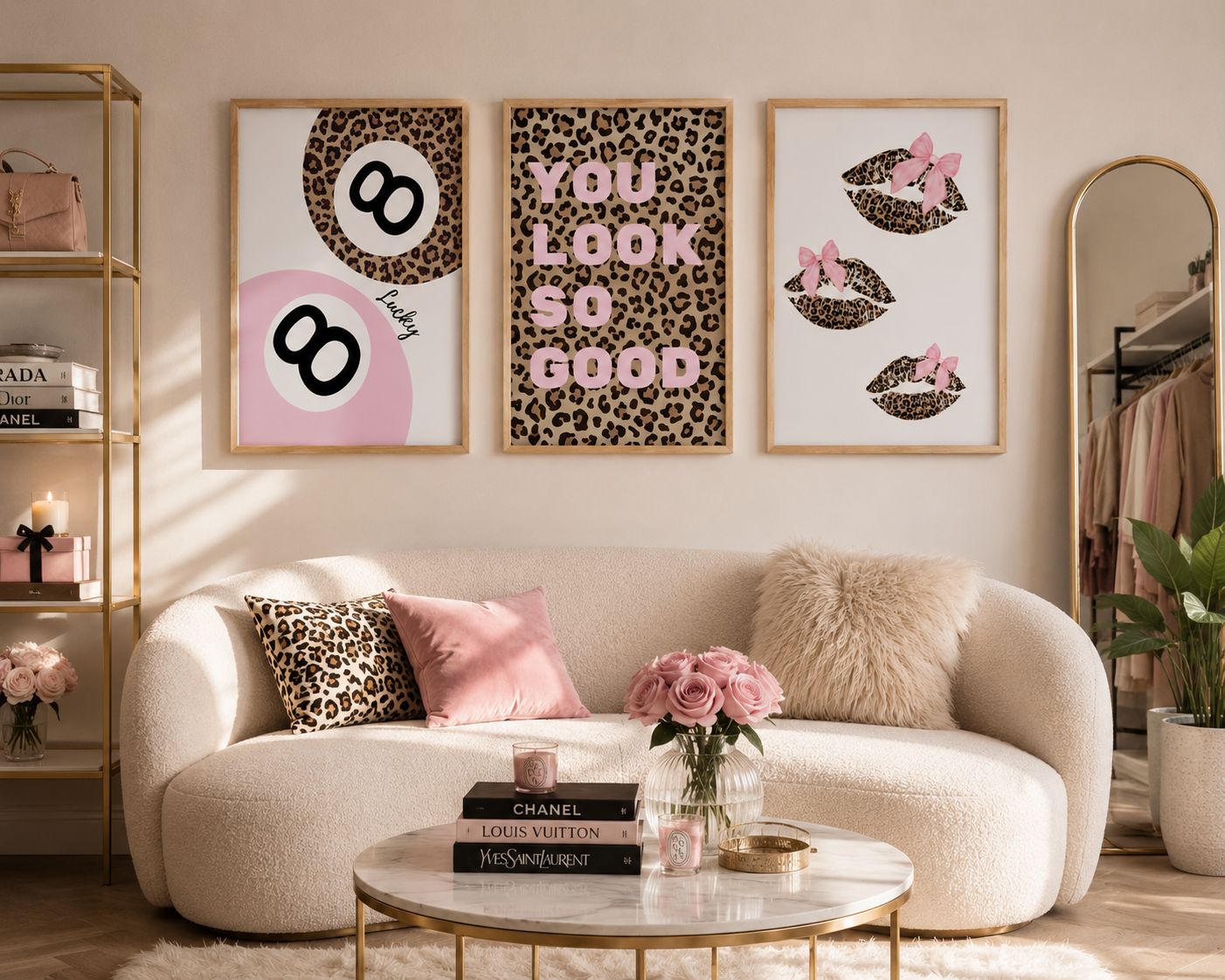 Three framed fashion-themed wall art prints with leopard print and pink accents hang above a cream boucle sofa in a styled living room. The prints feature an 80th birthday design, the phrase 'YOU LOOK SO GOOD', and pink bow-adorned lips.