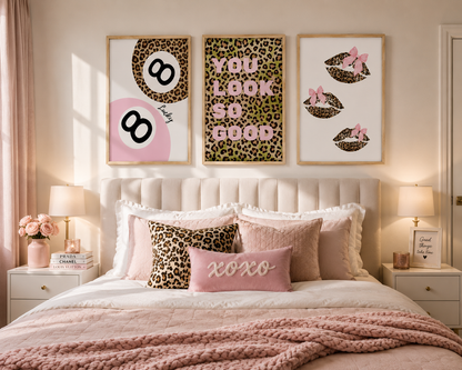 A styled bedroom scene with three framed wall art prints above a bed. The prints feature leopard print, pink circles, lips with bows, and the phrase 'YOU LOOK SO GOOD.