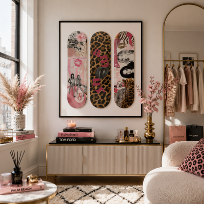 A framed wall art piece featuring three vertical skateboard decks with pink, leopard print, and graphic designs, displayed in a styled living room above a console table.