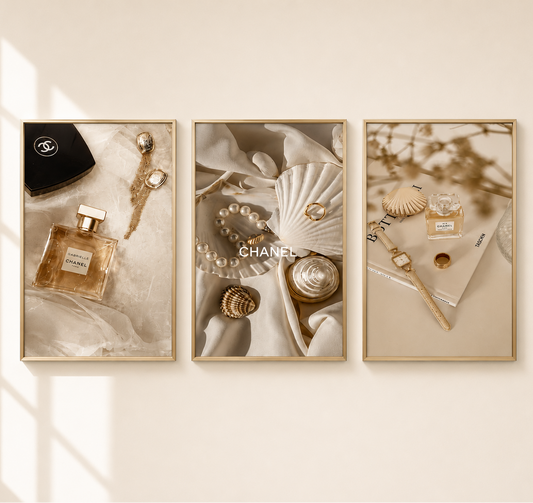 Three framed wall art prints with a warm beige and cream aesthetic, featuring Chanel perfume bottles, seashells, pearls, and a black Chanel box. The frames are displayed on a light beige wall with soft window shadows.