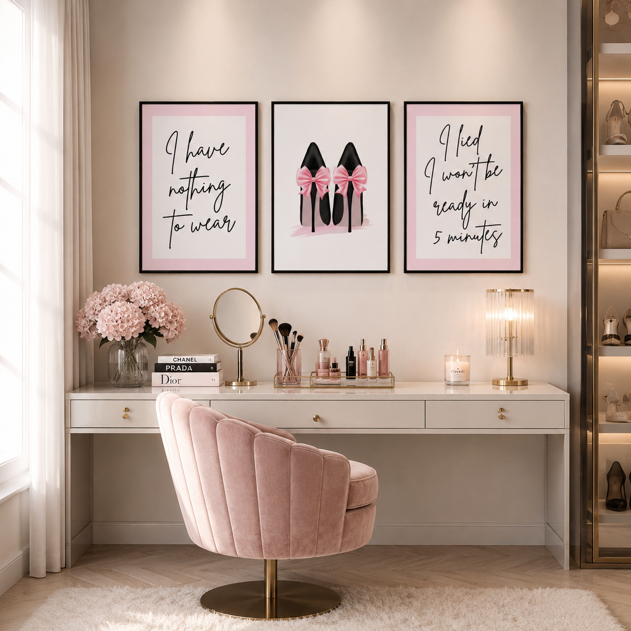 A styled vanity area with three framed motivational and fashion prints above a white desk and blush pink velvet swivel chair. The center print shows black high heels with pink bows, while the side prints contain handwritten text.
