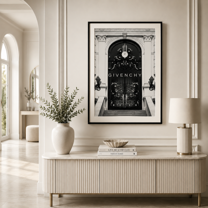 A framed black and white art print of a Givenchy architectural door hangs on a cream-colored wall above a ribbed console table in a styled interior room.